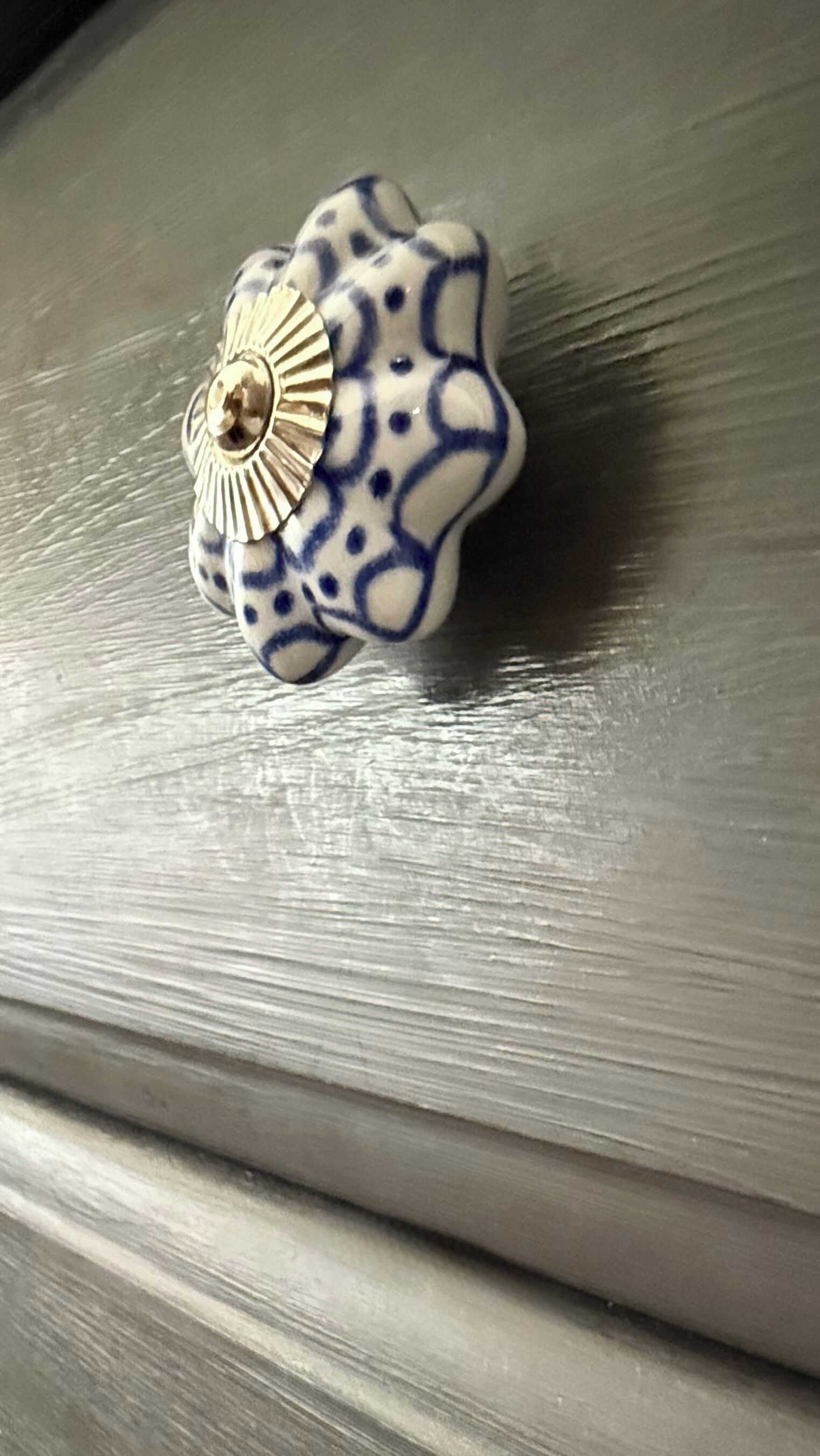 A ceramic object with a floral pattern and a gold center, placed on a wooden surface.