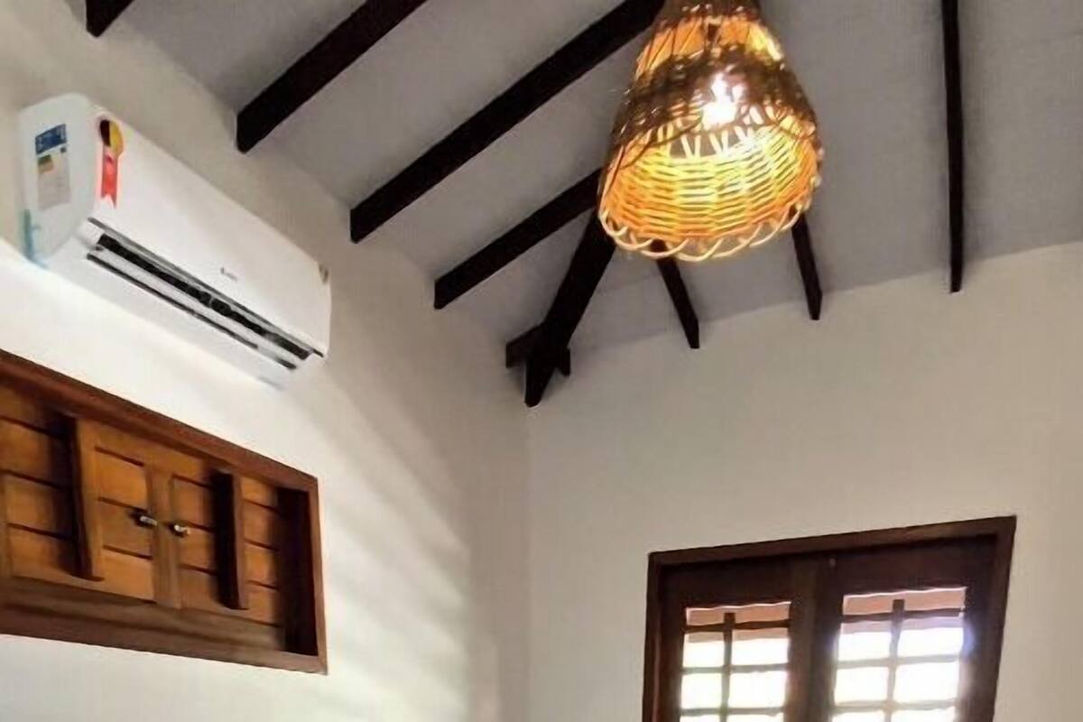 Une chambre à coucher comprenant un lit, une fenêtre, un luminaire suspendu et un appareil de climatisation.