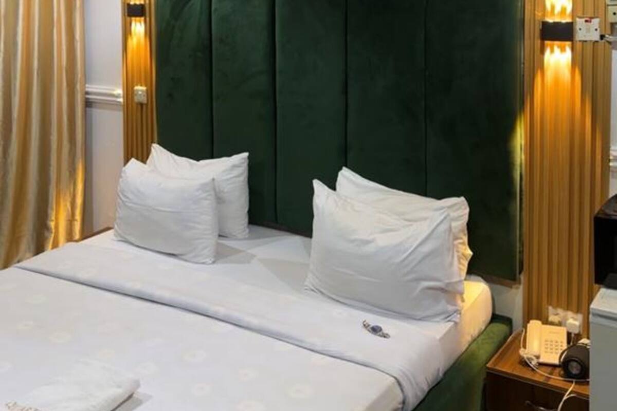 Una habitación de hotel con una cama grande, una mesita de noche con lámpara y cortinas.