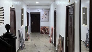 Un corridoio con pavimento piastrellato, pareti bianche e porte su entrambi i lati.