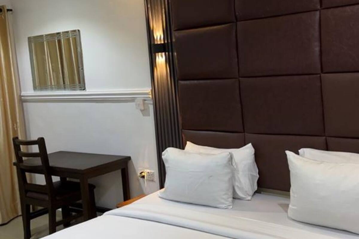 Una habitación de hotel con una cama grande, una mesita de noche y una silla.