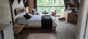 Une chambre confortable avec un lit, une petite table, une chaise et une vue sur l’extérieur.
