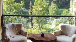 A room with two armchairs facing a large window overlooking a forested area. - Luxon Suit Bungalov (Camlihemsin)