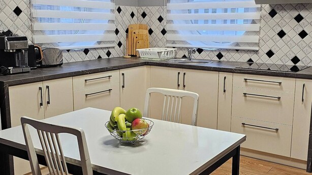 Una cocina moderna con una mesa de comedor, sillas y un frutero.