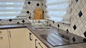 Una cocina con encimera de mármol negro, armarios blancos y salpicadero con diseño.