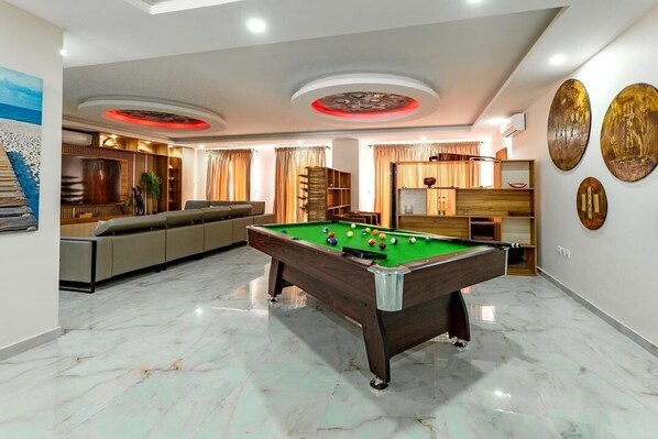 Une salle de billard équipée d’une table de billard, d’un espace détente et d’œuvres d’art décoratives murales.