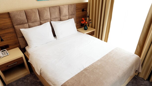 Une chambre d’hôtel avec un grand lit, une table de chevet avec une lampe et une petite table de nuit avec un téléphone.