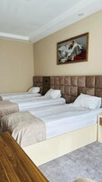 Une chambre d’hôtel avec deux lits, une table de chevet en bois et un tableau au mur.