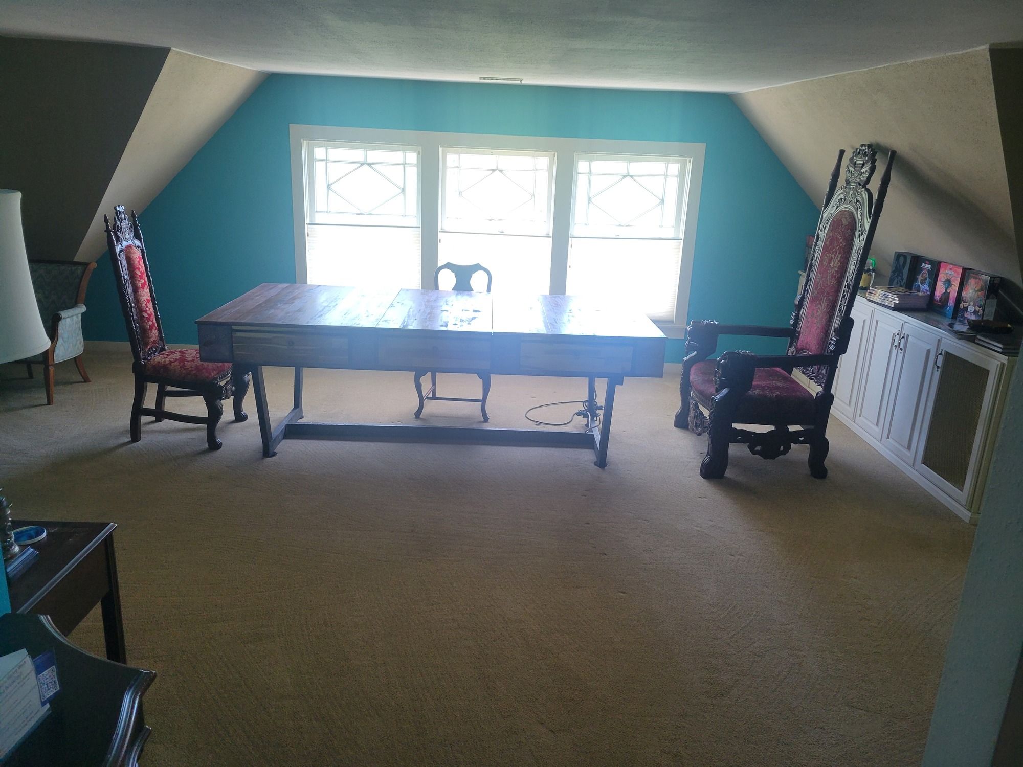 Comedor con una mesa grande y cuatro sillas, un mueble con objetos encima y una ventana con persianas.