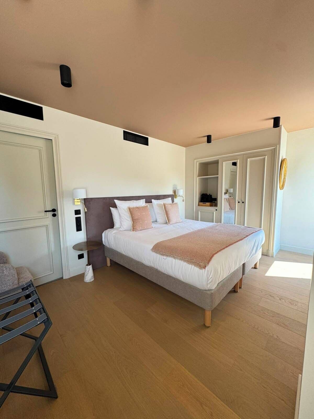 Ein Schlafzimmer mit einem Bett, Nachttischen, einem Kleiderschrank und einem Spiegel.