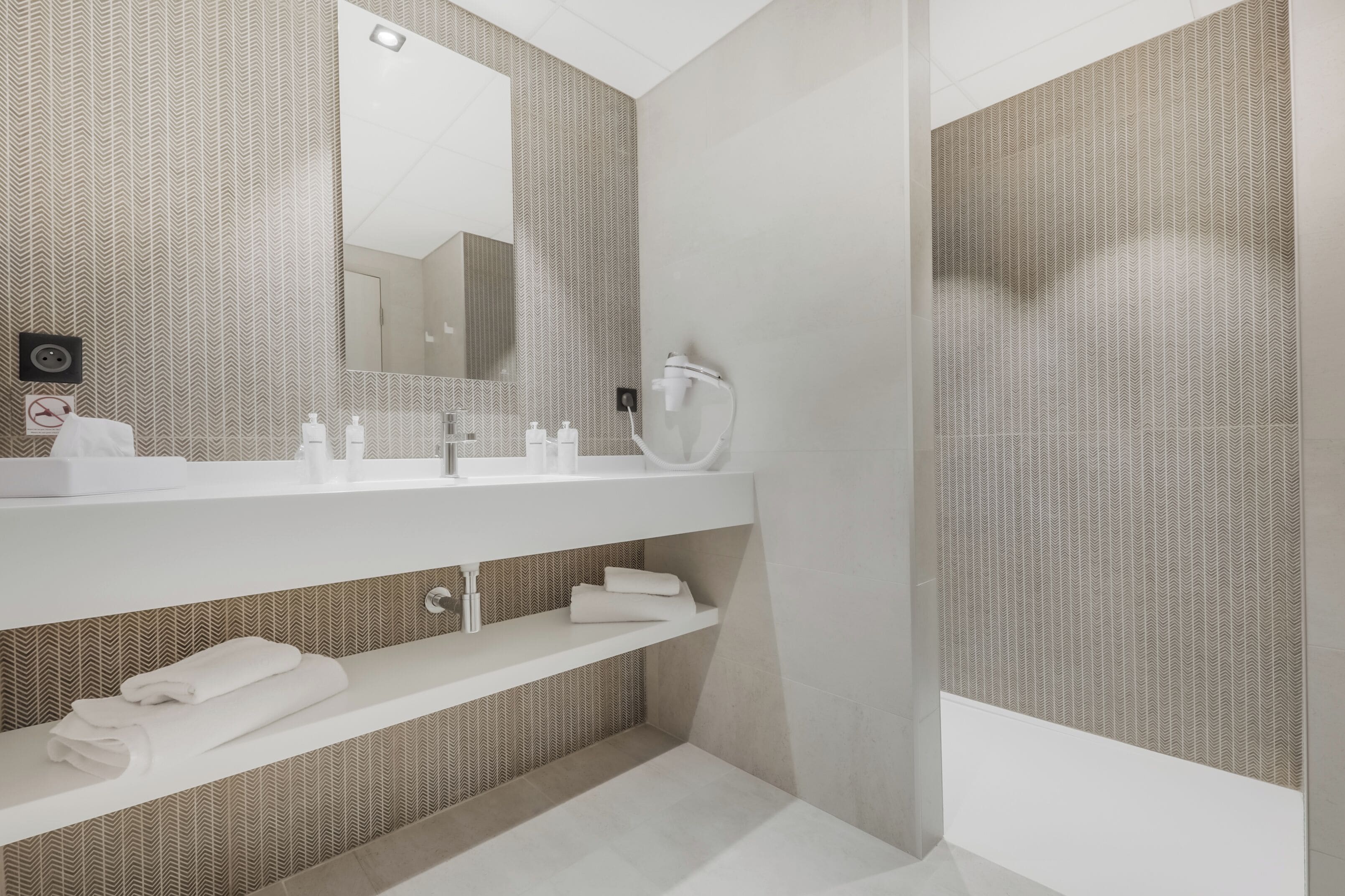 A modern bathroom with a large mirror, white vanity, and a towel rack.