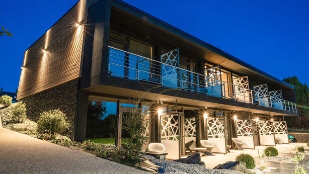 Una casa moderna de dos pisos con balcón, zona de estar exterior e ingreso bien iluminado.