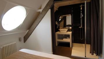 Un dormitorio con tragaluz, una cama grande, un baño con bañera y ducha.