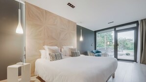 Un dormitorio moderno con una cama grande, un panel de madera decorativo y vistas al exterior.