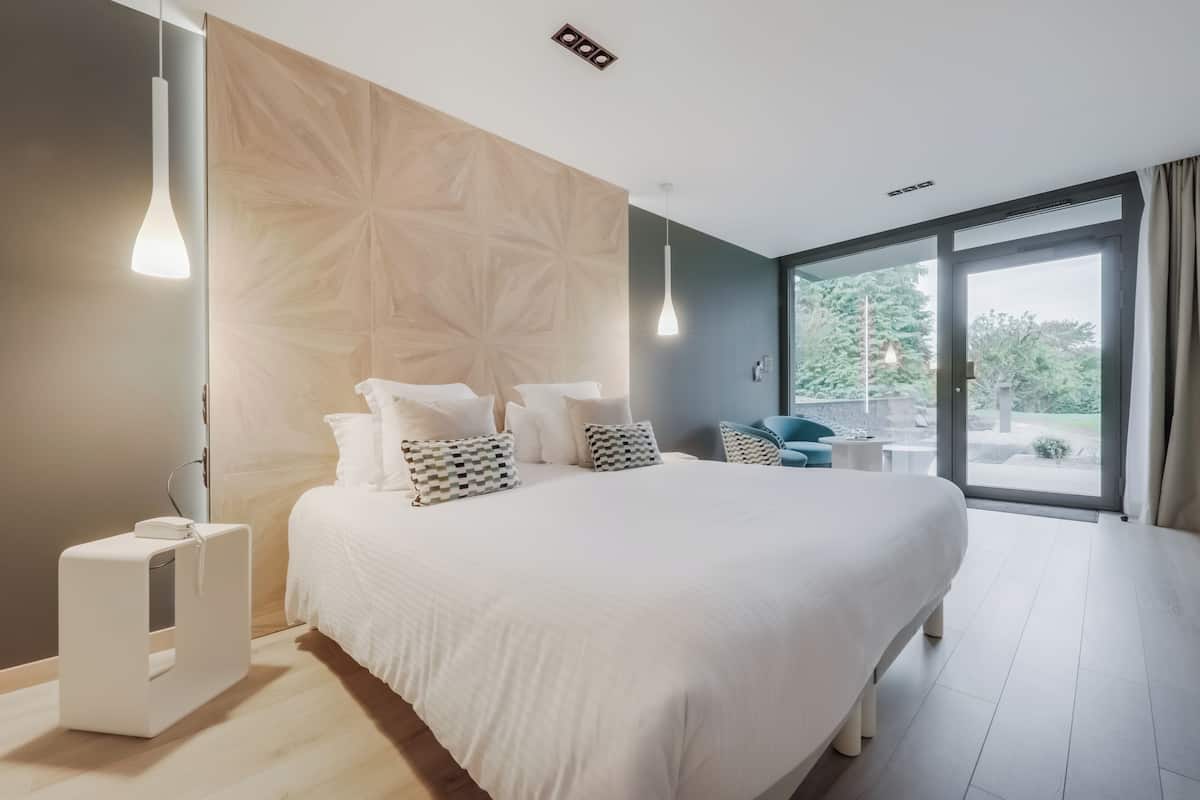 Un dormitorio moderno con una cama grande, un panel de madera decorativo y vistas al exterior.