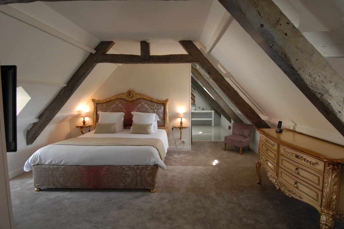 Un dormitorio con una cama grande, dos mesitas de noche con lámparas, un aparador y una silla.