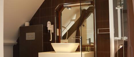 A modern bathroom with a glass-enclosed shower, a white sink, and a toilet.