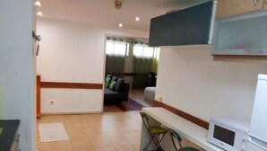 A compact kitchen with a microwave, a small dining area with two chairs, and a sofa in the background. - Apartamento Doria - Center Porto Economic Huge Fla (Porto)