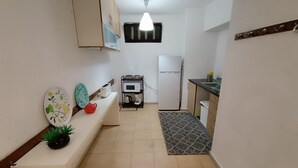 A compact kitchen with a built-in oven, a microwave, a refrigerator, and a small sink. There is a bench with a plant and decorative plates. - Apartamento Doria - Center Porto Economic Huge Fla (Porto)