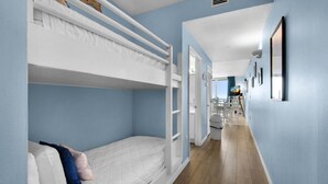 A room with bunk beds, a hallway, and a bathroom. - Inn At Summerwind 304 - Hooked on the Beach (Navarre)