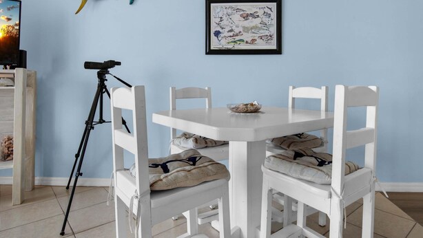 Un comedor con una mesa y sillas blancas, una decoración de pez en la pared y un mapa enmarcado.