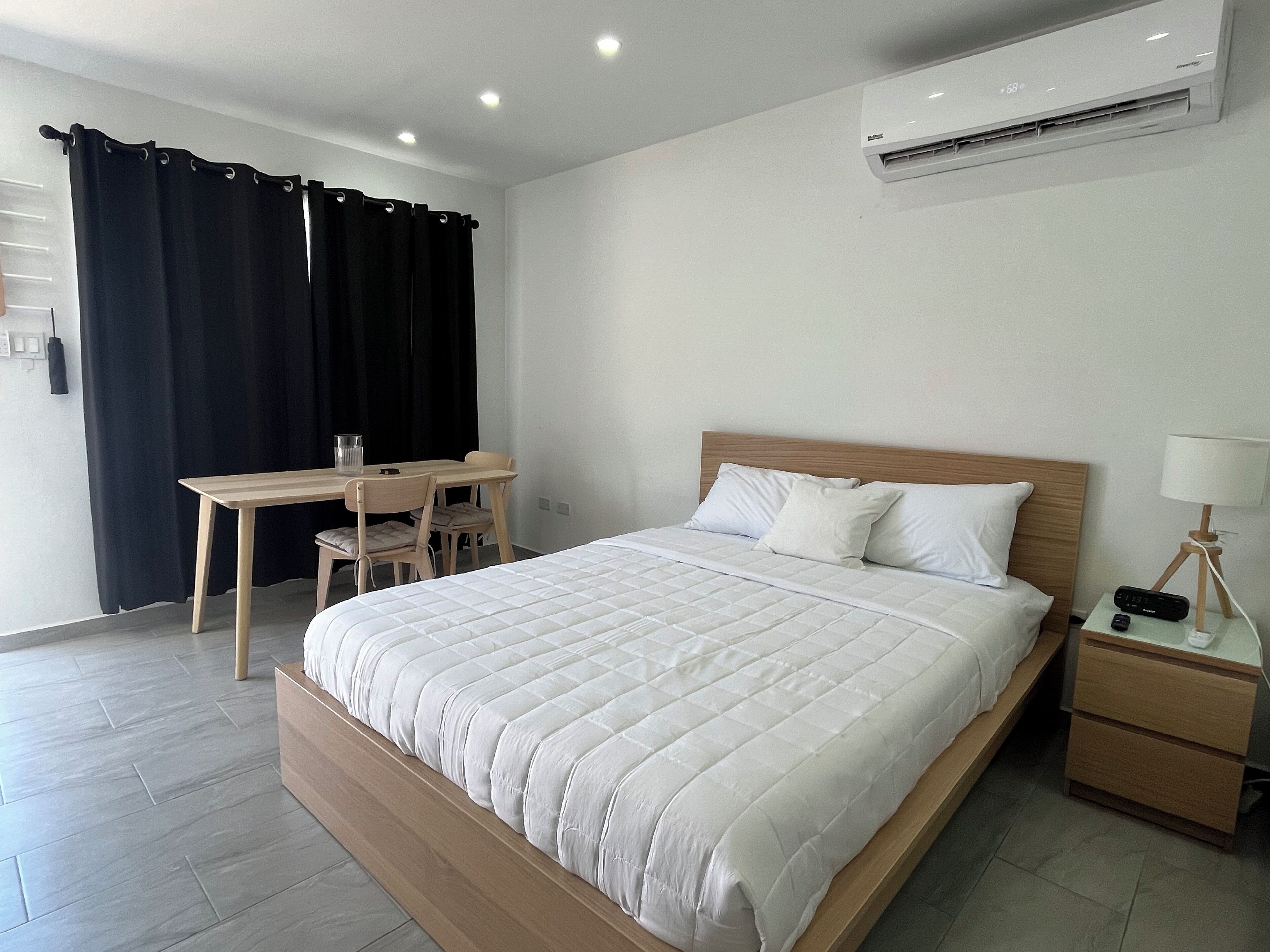 A modern bedroom with a large bed, a desk, and a chair.