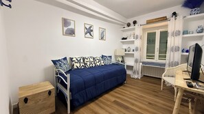 Un dormitorio con cama, mesita de noche y escritorio con ordenador.