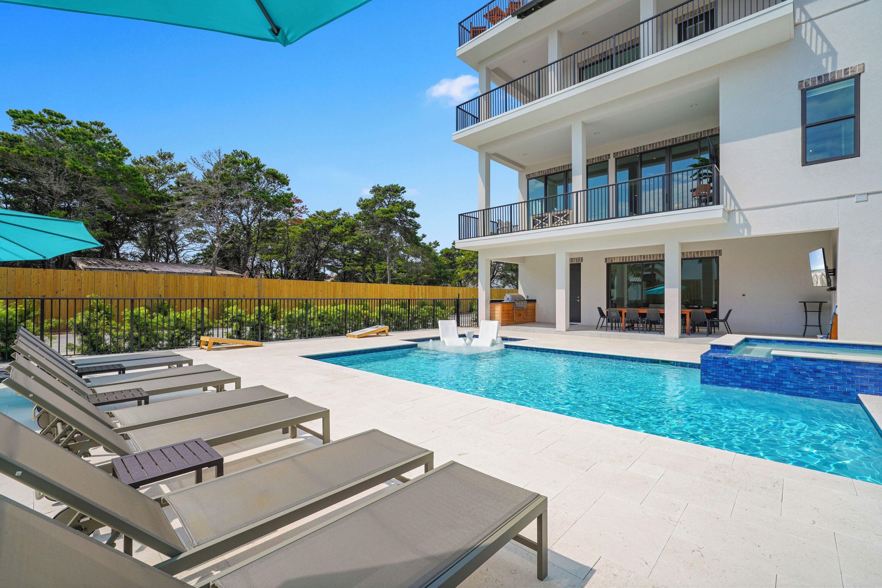 A modern building with a pool, lounge chairs, and a wooden fence.