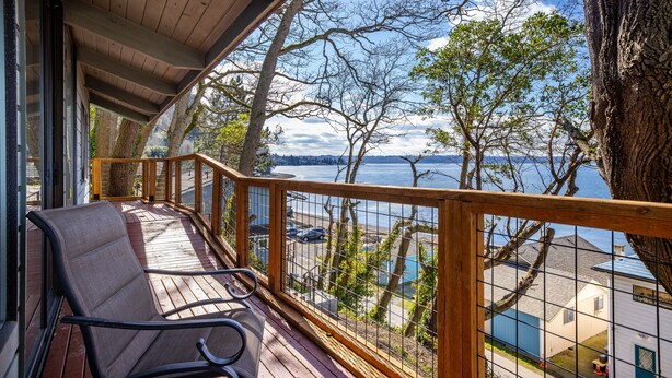 A wooden deck with a view of a lake and buildings. - Dash Point Retreat by the Beach with Amazing Water Views from Almost Every Room. (Tacoma)