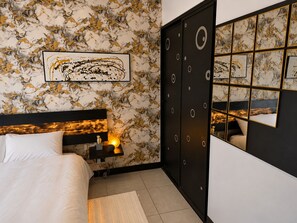 Un dormitorio con cama, mesita de noche, lámpara y armario con espejo.