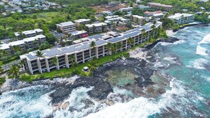 A coastal hotel with multiple buildings, solar panels on the roofs, and a rocky shoreline.