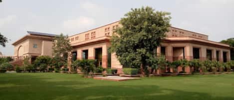A large building with a central courtyard, surrounded by greenery and trees.