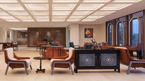Un vestíbulo moderno con techo alto, zonas de estar y paneles decorativos.