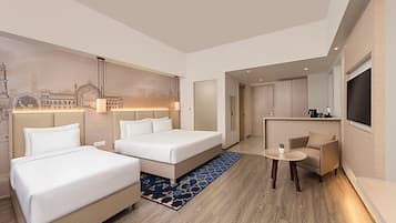 Una habitación de hotel con dos camas, un sofá, una mesita y un televisor.