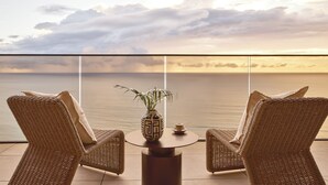 A balcony with wicker chairs, a small table, and a vase with a plant. - Mondrian Gold Coast (Burleigh Heads)