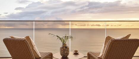 A balcony with wicker chairs, a small table, and a vase with a plant.