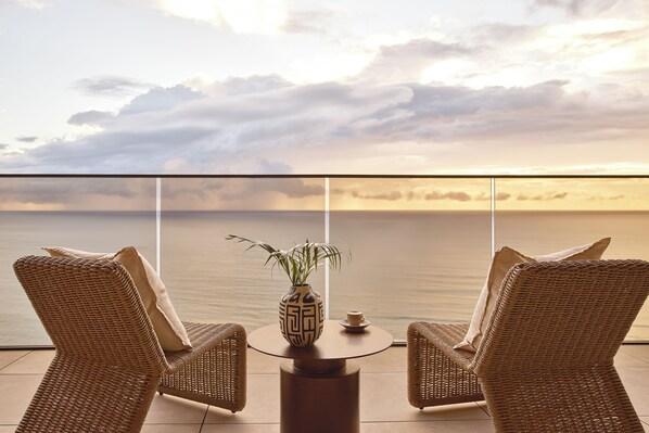 A balcony with wicker chairs, a small table, and a vase with a plant. - Mondrian Gold Coast (Burleigh Heads)