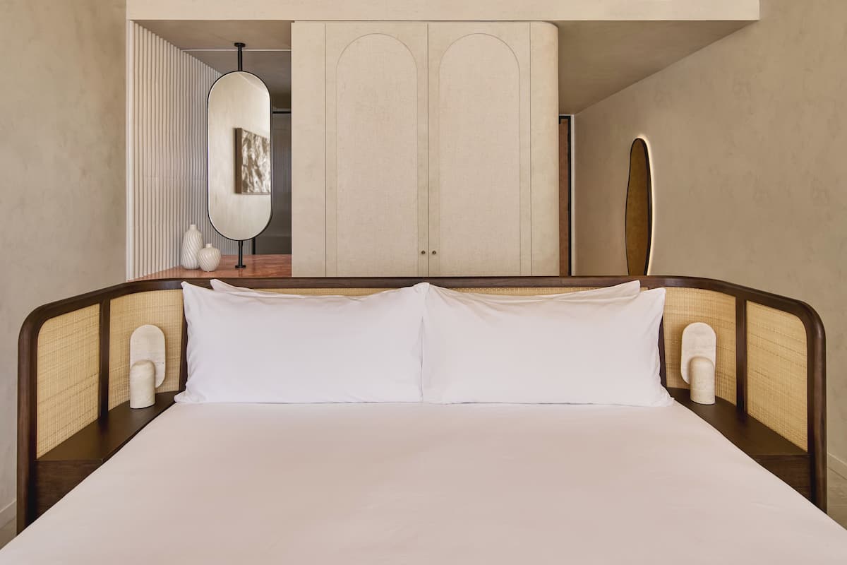 A bed with a wooden headboard, white bedding, and two bedside tables with lamps.