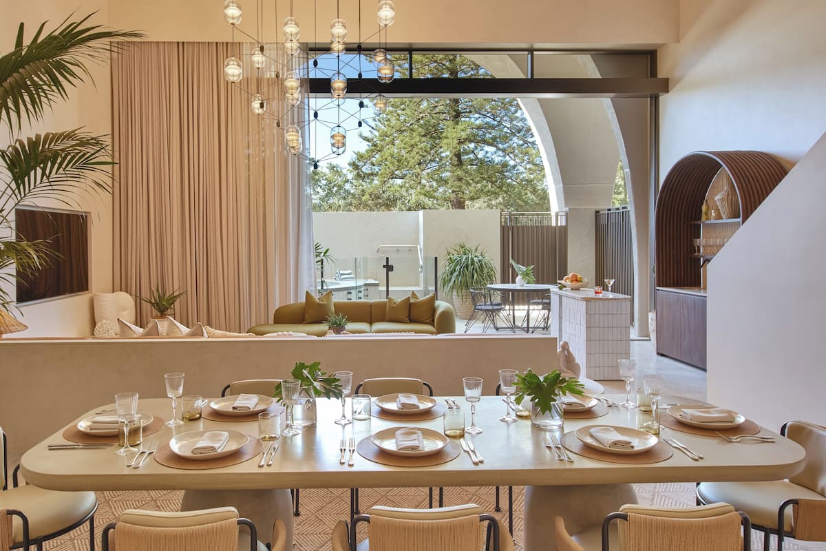 A modern dining area with a long table set for a meal, surrounded by comfortable seating.