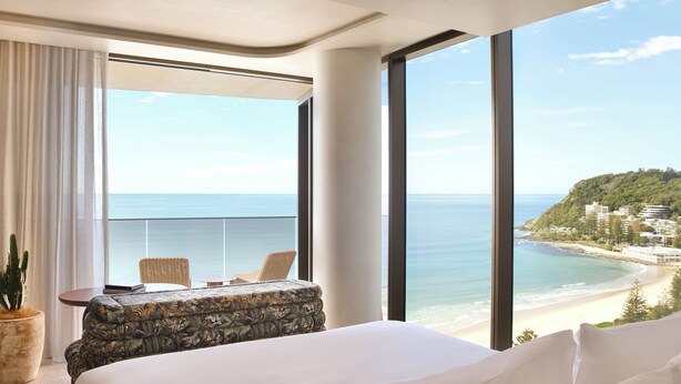 A hotel room with a large window offering a view of the beach and ocean. - Mondrian Gold Coast (Burleigh Heads)
