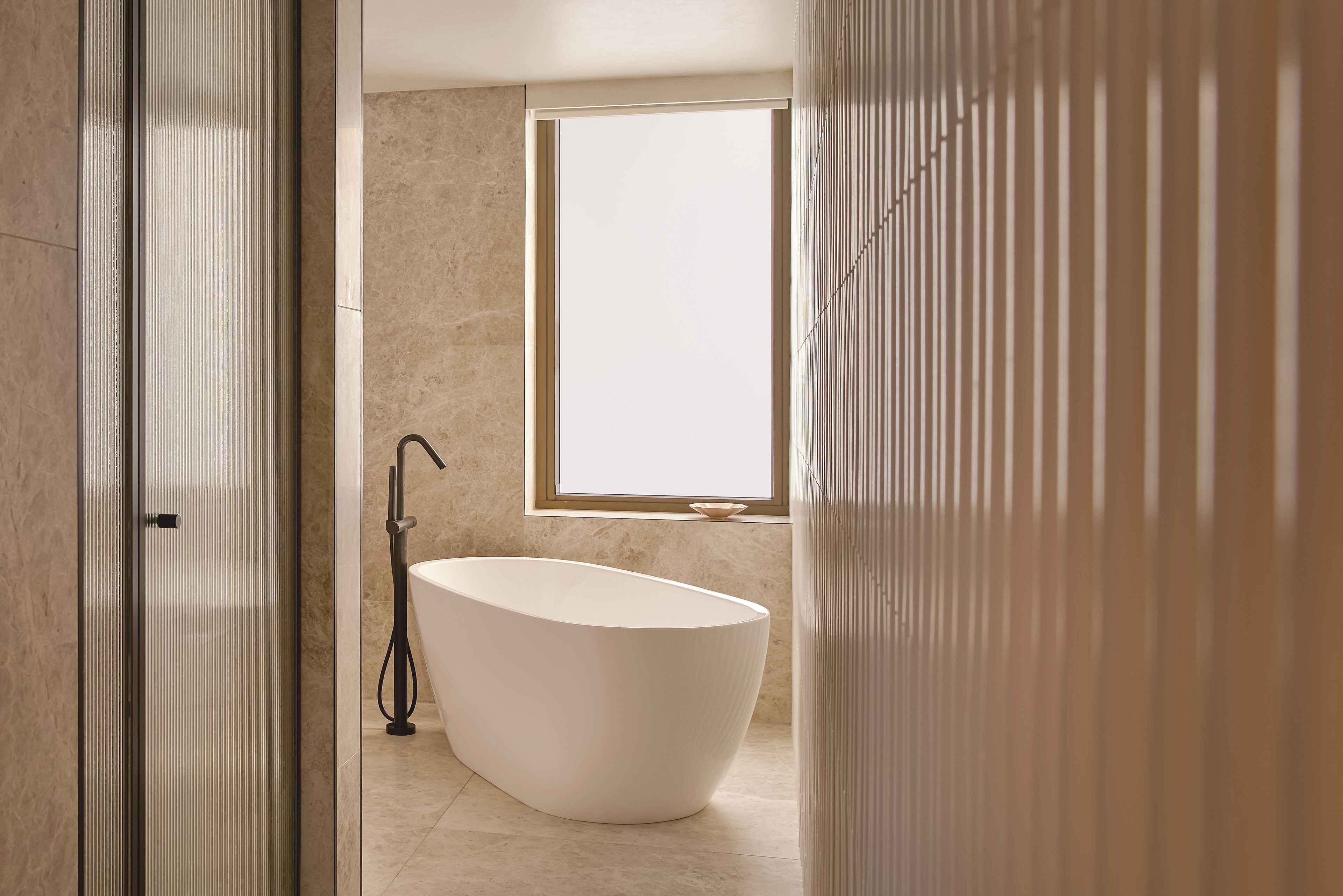 A modern bathroom with a freestanding bathtub, a window, and a shower area.
