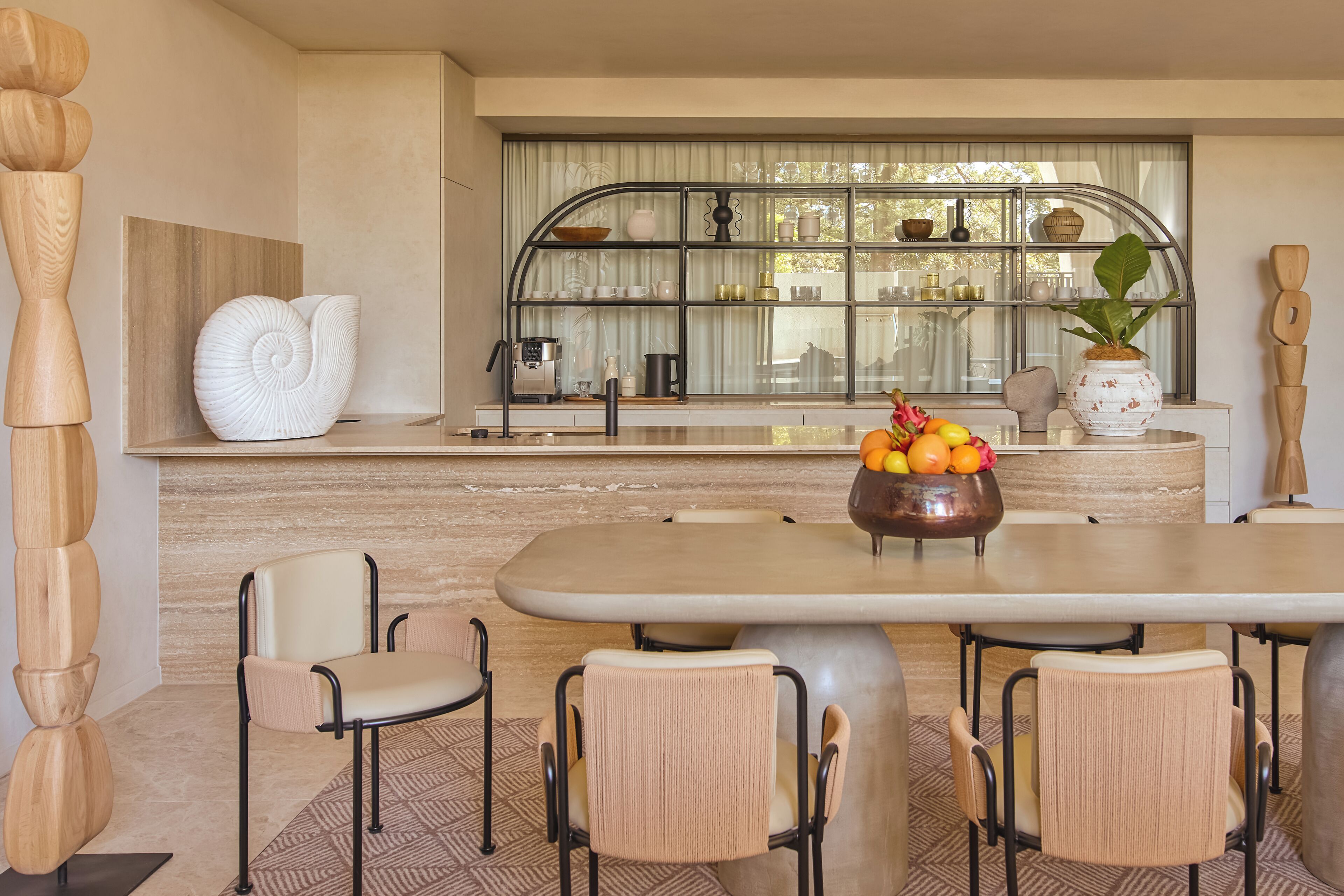 Une cuisine moderne dotée d’un grand îlot central, d’un coin repas avec quatre chaises et d’une fenêtre donnant sur l’extérieur.