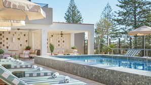 A poolside area with lounge chairs, a seating area, and umbrellas. - Mondrian Gold Coast (Burleigh Heads)