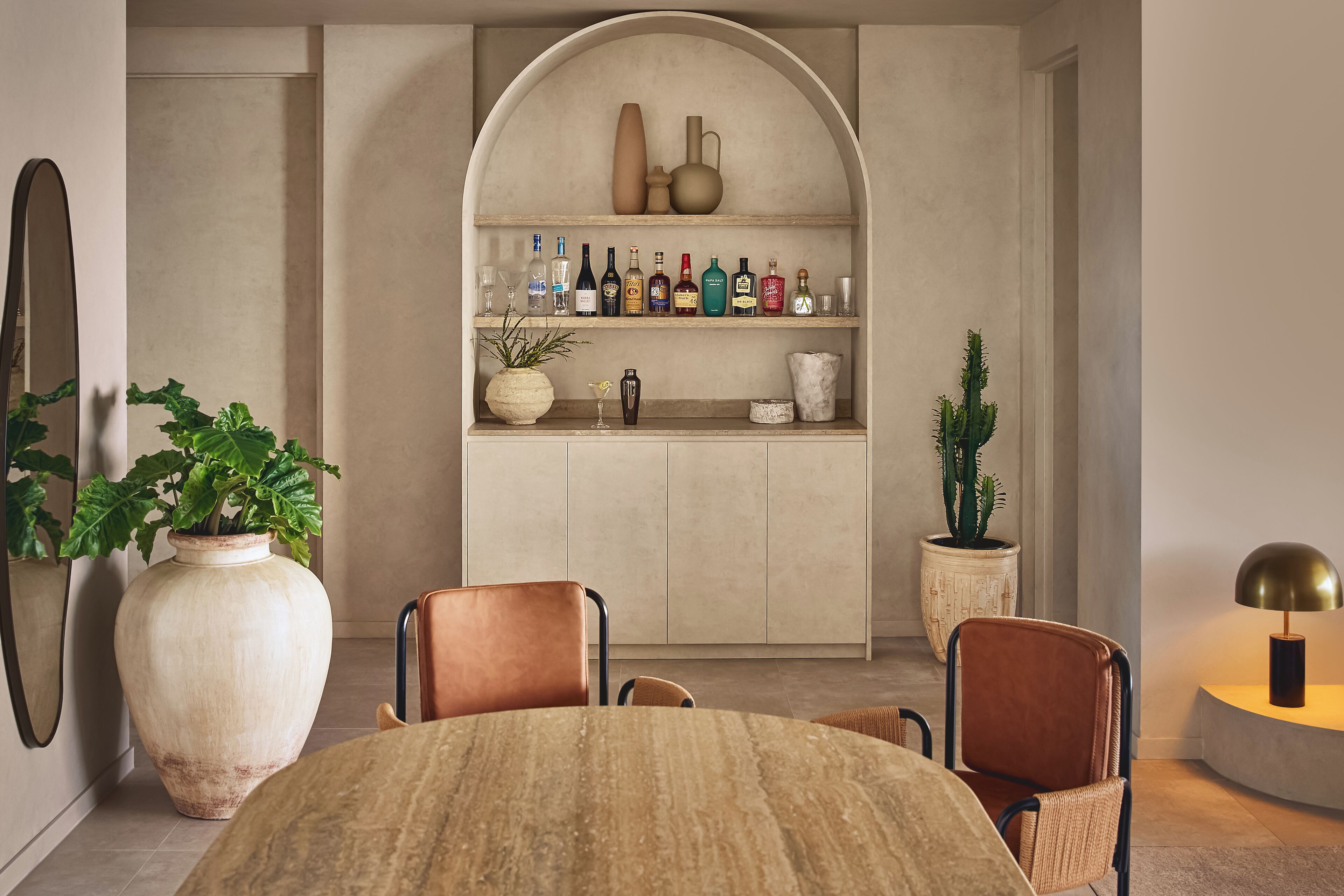 A dining area with a round table, two chairs, a large vase, and a potted plant.