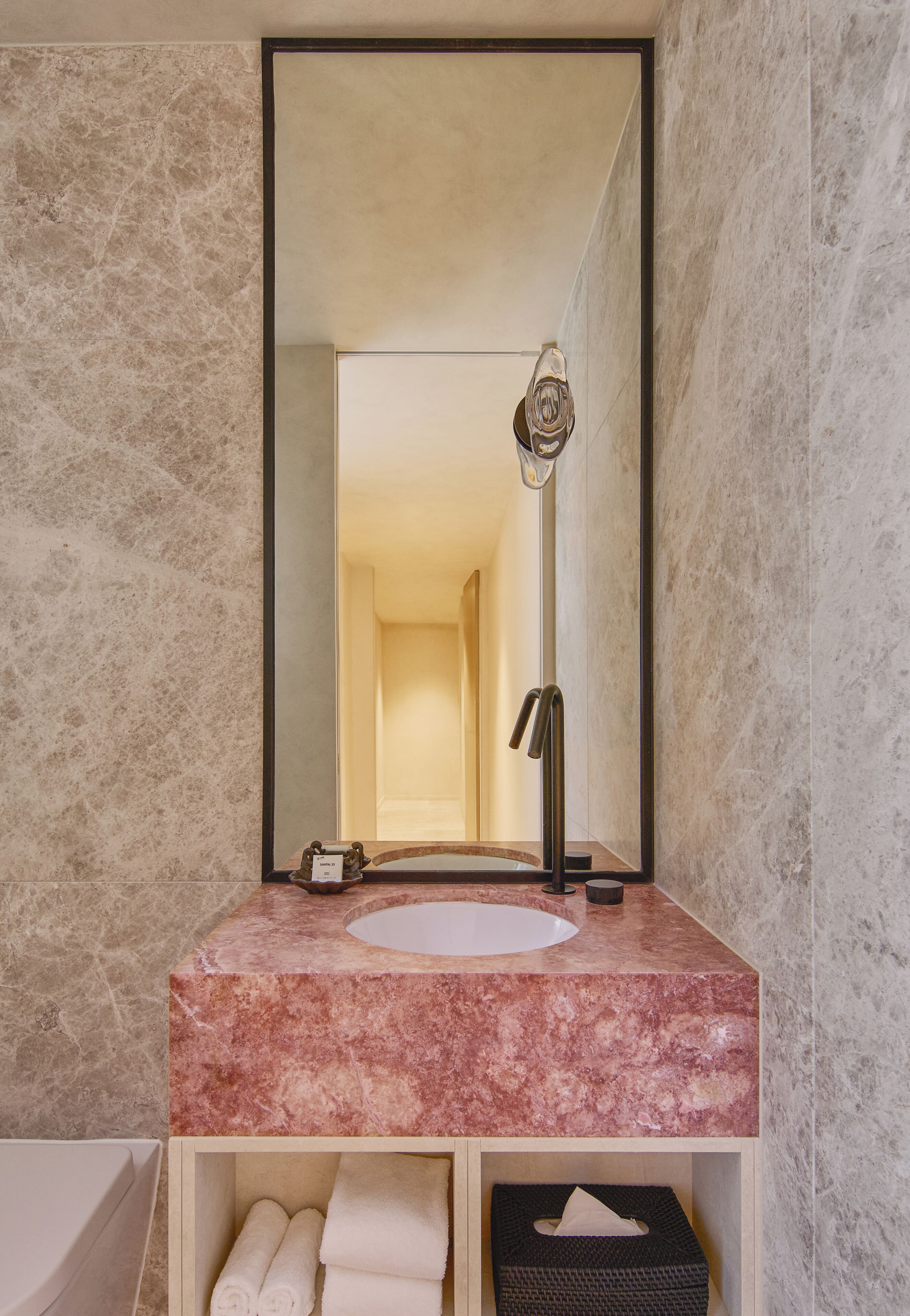 Une salle de bain avec un lavabo en marbre, un miroir et un porte-serviettes.