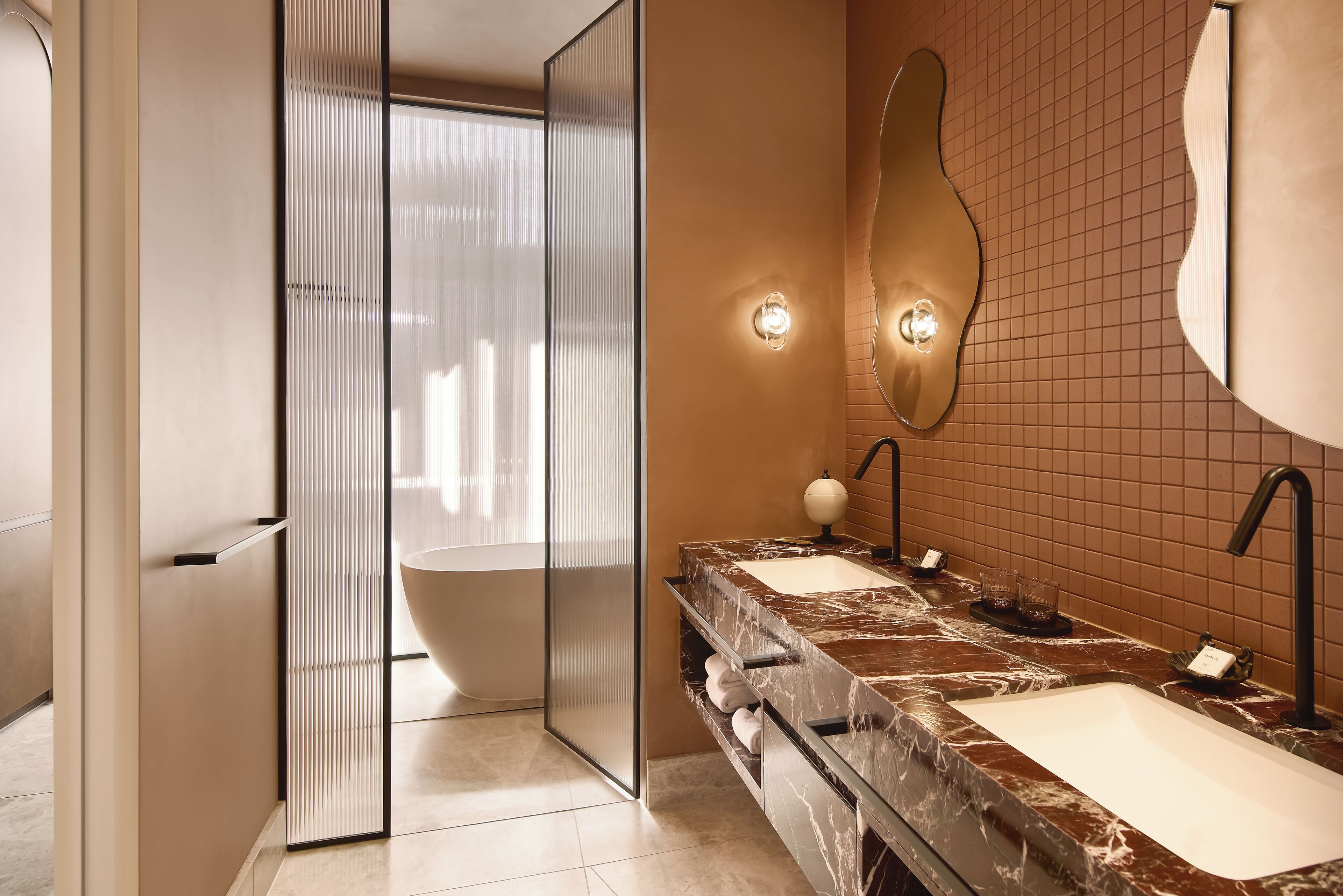 A modern bathroom with a large bathtub, two sinks, and a glass shower enclosure.