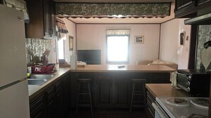 A compact kitchen with wooden cabinets, a refrigerator, a microwave, and a stove. - Charming 3-bedroom, 2 bath-room house with WiFi and AC in Lewes. (Lewes)