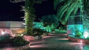 A nighttime pathway flanked by trees and illuminated by soft lighting. - Panorama Luxury Villa in Sitia, Crete (Sitia)