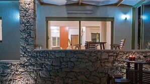 An outdoor patio area with stone walls, a seating arrangement, and a view into the interior of the building. - Panorama Luxury Villa in Sitia, Crete (Sitia)