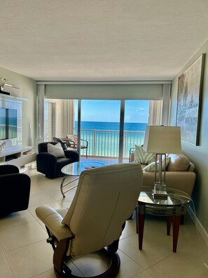 A modern hotel room with a balcony overlooking the sea, a glass coffee table, a sofa, and a chair. - Beachfront Paradise with Stunning Gulf Views – Your Naples Escape Awaits! (Naples)